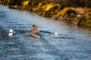 Two women rowing canoe in a river to burn excess body fat