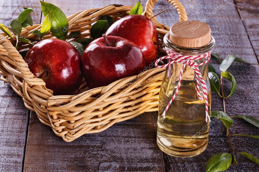 Apple cider vinegar and red apples in a basket
